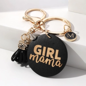 Close-up of black wooden keyring with golden GIRL mama engraving and black tassel accessory