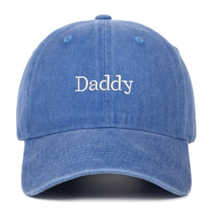 Close-up of white Daddy embroidery on washed blue cotton baseball cap with curved brim
