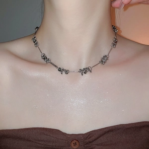 Close-up of metallic beaded chain necklace featuring twisted silver circles and tassels