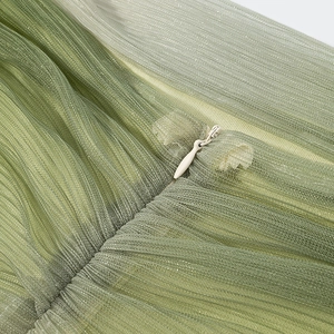 Detail view of green gradient mesh fabric with pleated texture and invisible zipper closure
