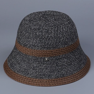 Detail of woven straw bucket hat featuring metallic flower accent and pearl center