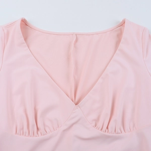 Détail du décolleté en V profond et des coutures plissées de cette robe rose