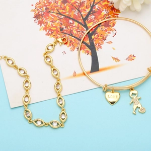 Detailed shot of golden charm bracelet featuring a LOVE heart and zircon boy pendant