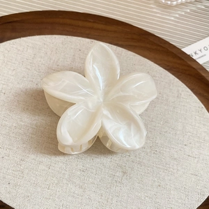 Vue détaillée d'une pince à cheveux en fleur acrylique marbrée sur un plateau en bois