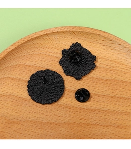 Detail view of black metal pins backs and clutch fasteners on a wooden tray