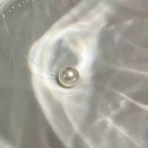 Macro detail of round pink pearl pendant with invisible thin line necklace string