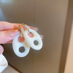 Gros plan détaillé de boucles d'oreilles dorées avec strass et pendentif en résine blanche