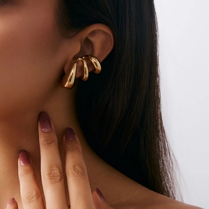 Macro shot of minimalist gold C-shaped ear cuff with smooth polished geometric curves