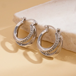 Close-up of silver double-layer geometric hoop earrings with clear crystal rhinestones