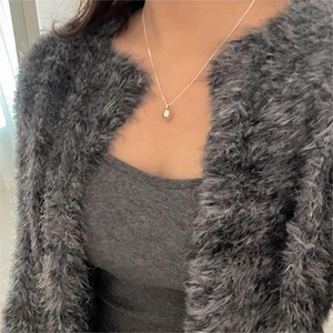 Detail of silver water-drop pendant necklace worn with a minimalist grey cardigan