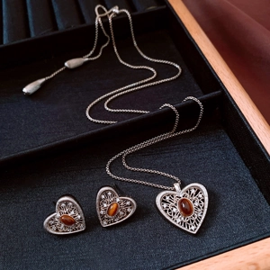 Detailed close-up of vintage heart jewelry set with brown gemstones on velvet tray