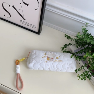 Close-up of quilted white pencil case with cute rabbit embroidery and yellow zipper