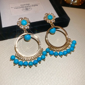 Detail of bohemian daisy earrings with gold plating, white diamonds and turquoise beads