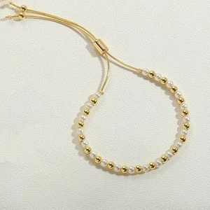 Macro detail of 14K gold plated bead bracelet with white pearls and adjustable slider clasp