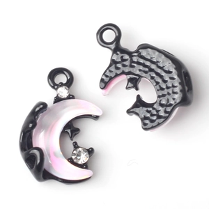 Macro detail of moon-shaped charms showing pearlescent inlay and black metal texture