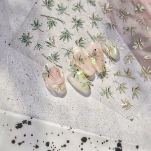 Macro shot of gold laser bamboo leaf nail stickers with green glitter on manicured nails