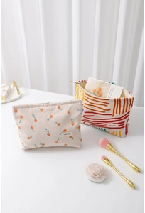 Detail of floral and striped corduroy makeup bags with gold zippers and brand labels