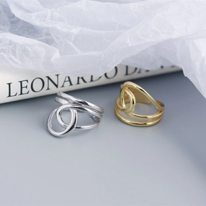 Macro detail of intertwined silver and gold double-layered open rings on textured paper