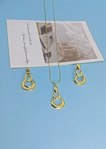 Detailed view of gold triple-loop teardrop necklace and earring set on blue background