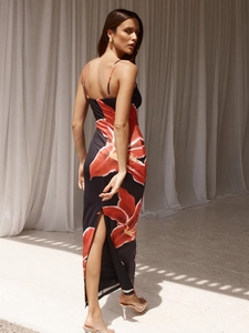 Rear view of a floral summer dress with thin straps and a slit on black silk fabric