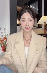 Détail d'un collier de perles double couche avec pendentif en métal sur une veste en tweed