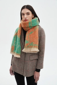 Detail of checkered bouclé knit scarf with fringe in orange and green tones