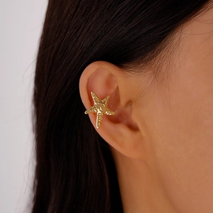 Close-up of a golden starfish ear cuff featuring a textured metallic finish for women