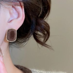 Close-up of retro rectangular flocked earrings in dark brown with gold textured borders