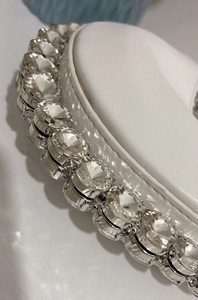 Close-up of a sparkling tennis chain featuring clear stones in a silver four-prong setting