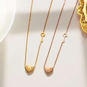 Detail of gold and rose gold lock heart necklaces featuring Love Forever 520 engraving