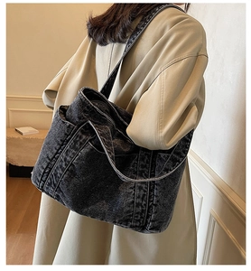 Dark gray denim tote bag shown worn by model in a minimalist indoor setting