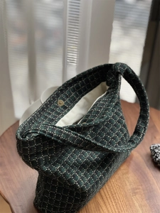 Close-up of vintage plaid wool bag featuring gold magnetic clasp and beige lining