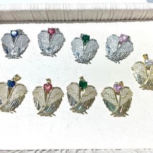 Polished angel wing heart pendants with pavé zircons in various colors on jewelry tray