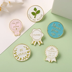 Set of six motivational enamel pins in pastel colors with gold metal edges on a soft background