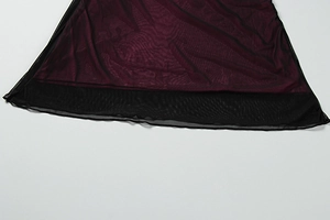 Detail of burgundy fabric layered with black translucent mesh on the dress hem
