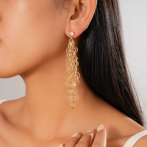Gros plan sur des boucles d'oreilles pampilles dorées avec cercles et pierres en zircon