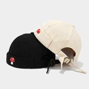 Retro docker hats in black and beige featuring unique red mushroom embroidery and metal buckle