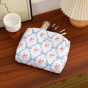 Quilted floral makeup bag featuring blue bows, pink roses, and internal storage detail
