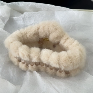 Close-up of cream plush hair claw clip showing soft faux fur and inner plastic teeth