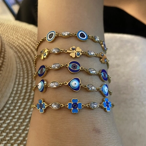 Nahaufnahme vergoldeter Armbänder mit blauen Böser-Blick-Anhängern und Zirkonia-Steinen