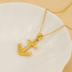 Gold-plated anchor pendant necklace with sparkling cubic zirconia on a ceramic dish