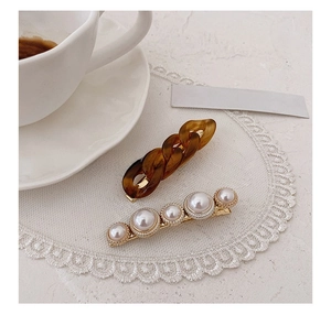 Detail of amber chain hair clip and white pearls set against elegant French decor