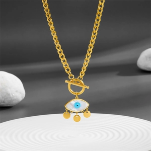 Gold Evil Eye necklace with natural shell pendant and blue crystal on textured white plate