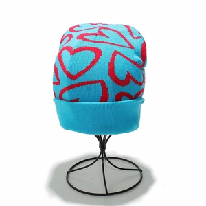 Detail view of sky blue knit beanie featuring red heart patterns and ribbed cuff texture