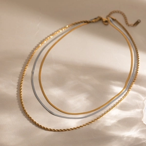 Detail view of multi-layer necklace with gold twisted and silver snake chains