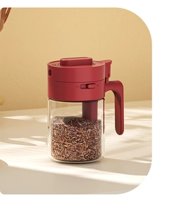 Detail view of transparent glass spice jar with integrated red lid and spoon handle