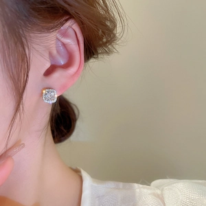 Close-up of a model wearing a square halo stud earring with sparkling cubic zirconia