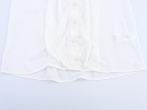 Detailansicht der weißen Plissee-Bluse mit 3D-Handarbeitsblumen und Kunstperlen