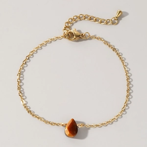 Macro view of gold chain bracelet with teardrop tiger eye stone and lobster clasp