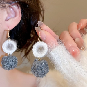 Dettaglio di orecchini a uncinetto con pompon grigi in ecopelliccia invernale
